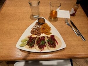 A delicious assortment of tacos on a plate with a drink beside it, placed on a dining table.