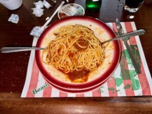 A plate of spaghetti topped with meat and rich tomato sauce, garnished with herbs.