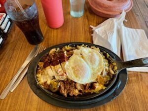 A plate with a fried egg sits on a table next to a glass of drink, creating a simple breakfast setting.