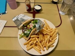 A plate featuring golden fries alongside a savory gyro, garnished with fresh vegetables.
