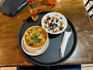 Grilled steak on a sizzling platter, accompanied by eggs, potato hash, and toasted bread. A bottle of A1 sauce and drinks included.